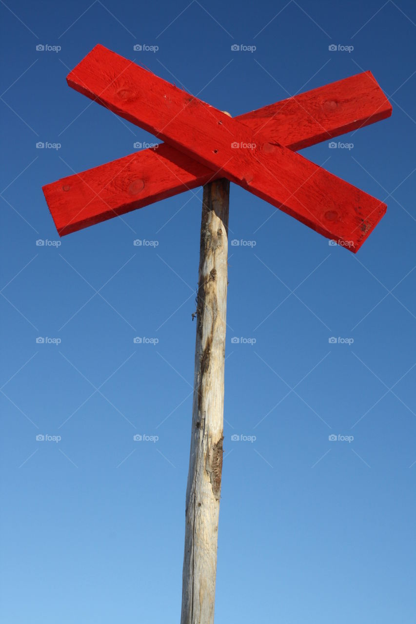 Red painted road sign against clear sky