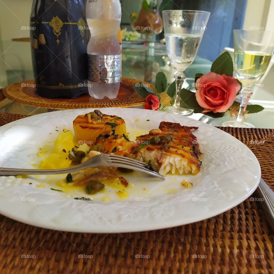A delicious fish with potatoes and a white  wine