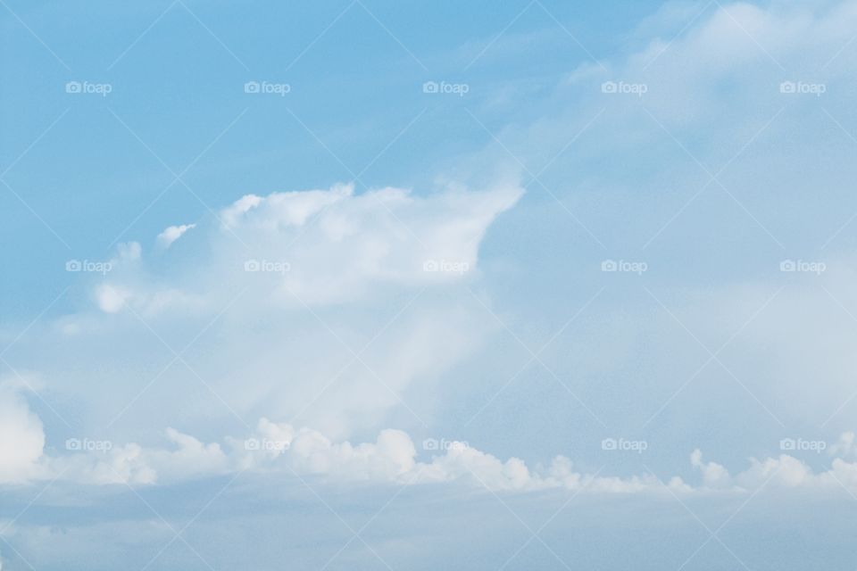 Towering white clouds against a pale blue sky