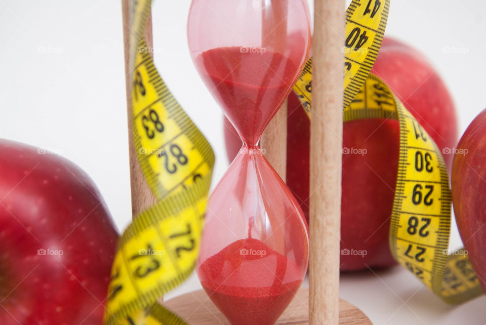 Luse weight concept. Measuring metter with red apples and sandglasses. Fat burning diet fitness.