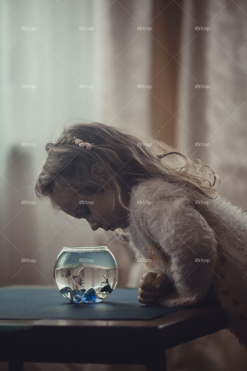 Girl with fish in round aquarium.