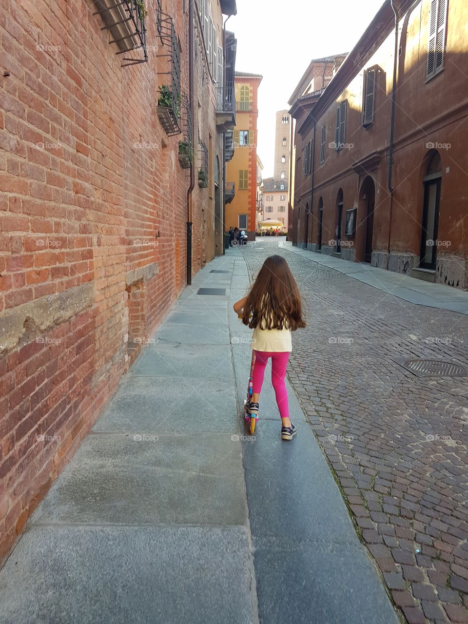 Little girl playing with a skate in a italian city street