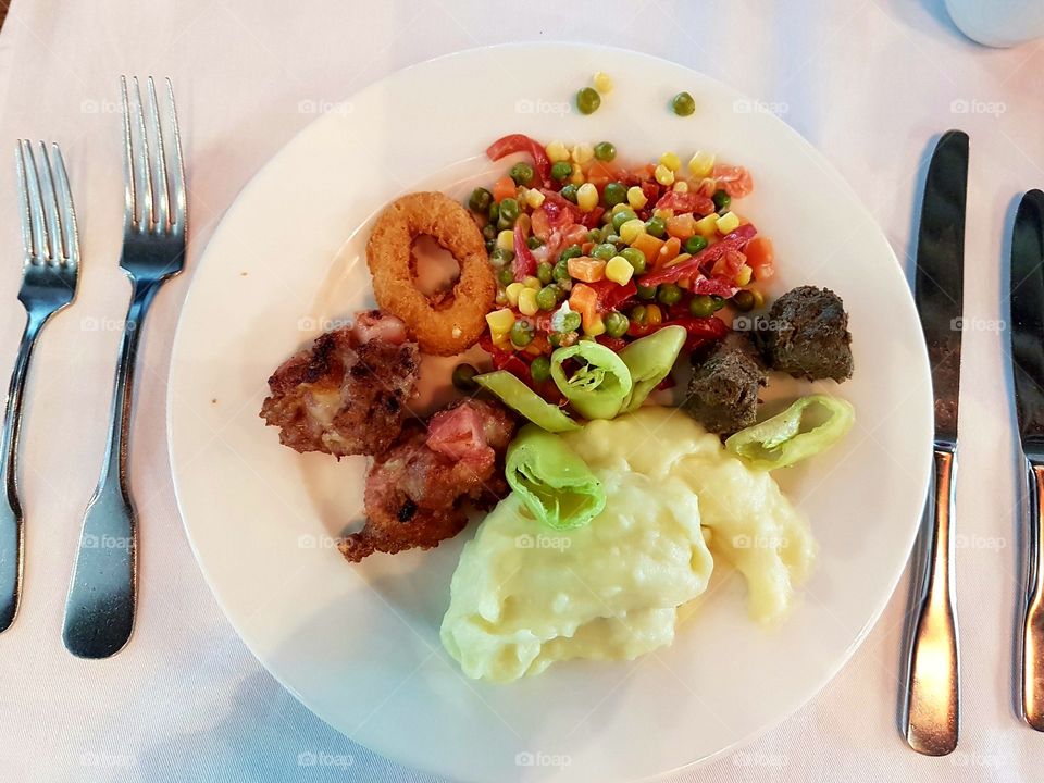 Dinner time. Plate with tomato, fish, liver and meat.
