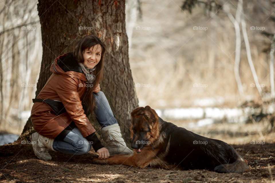 Young woman and German shepherd young male dog walking outdoor at spring day