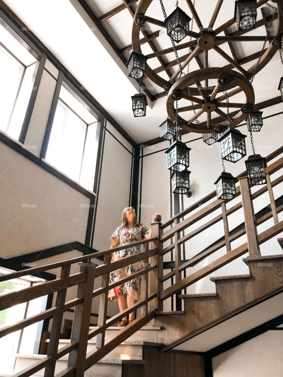 Wooden stairs, wooden circle chandelier, and woman in dress 