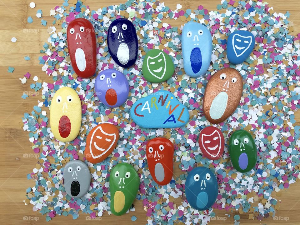 Carnival time with multicolored painted stones over confetti