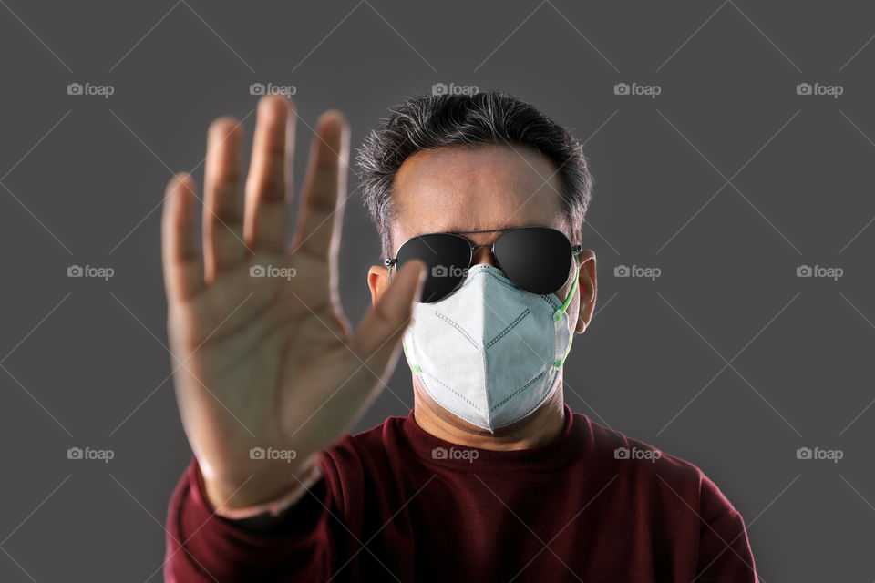 Indian man wearing a mask shows stop sign to Coronavirus, diseases, pollution, dust