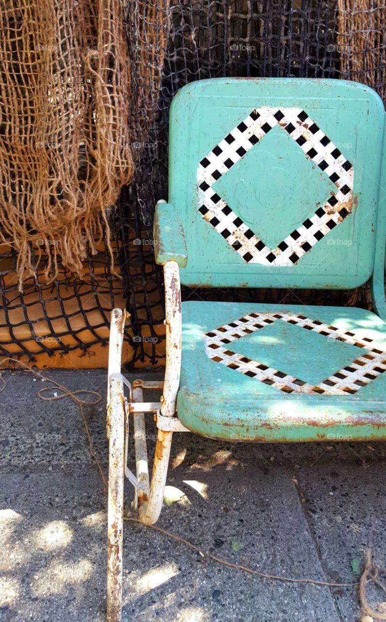 A vintage metal chair sits in the summer shade.