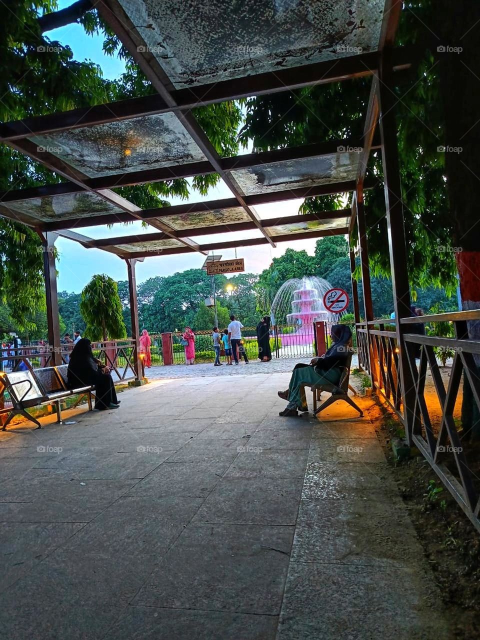 The scene looks so peaceful and relaxing! It's lovely to see people enjoying a sunny day under the shade. 🌞🌿