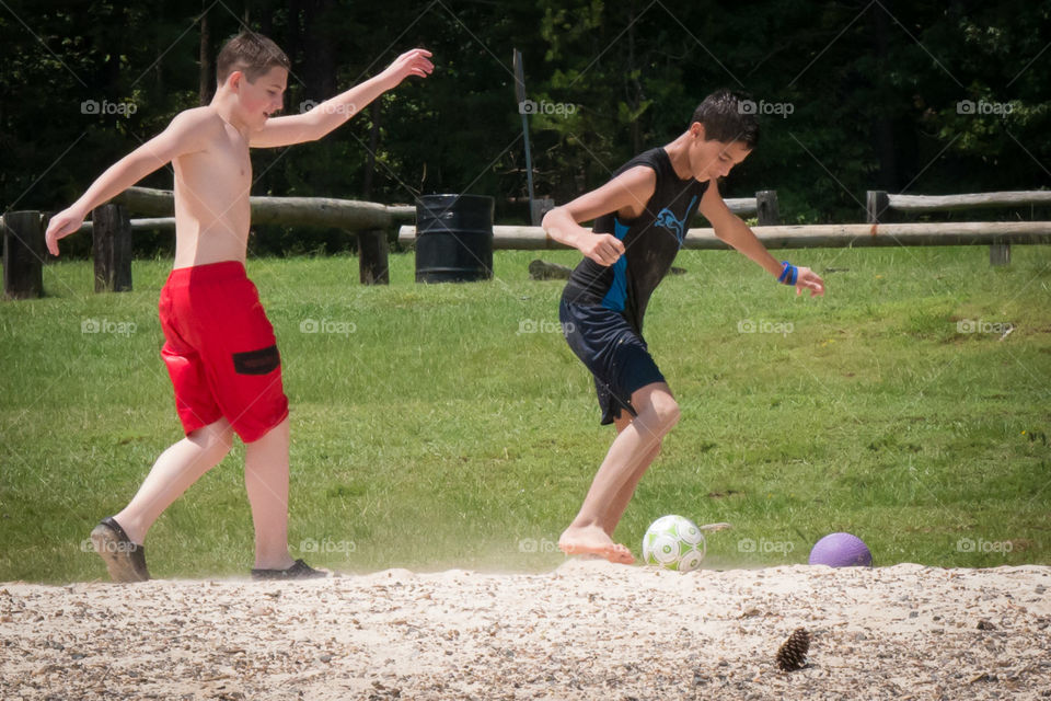 Cousins having fun . Family day at the lake. Cousins playing some soccer together 