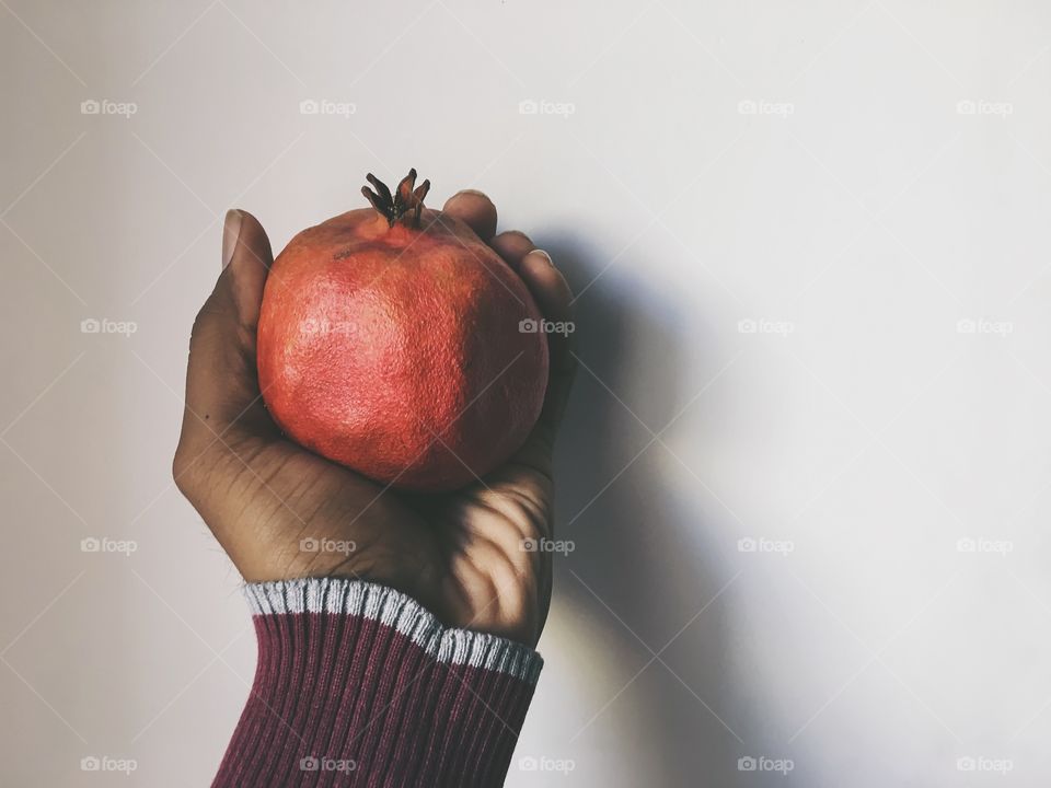 Person holding pomegranate against white background