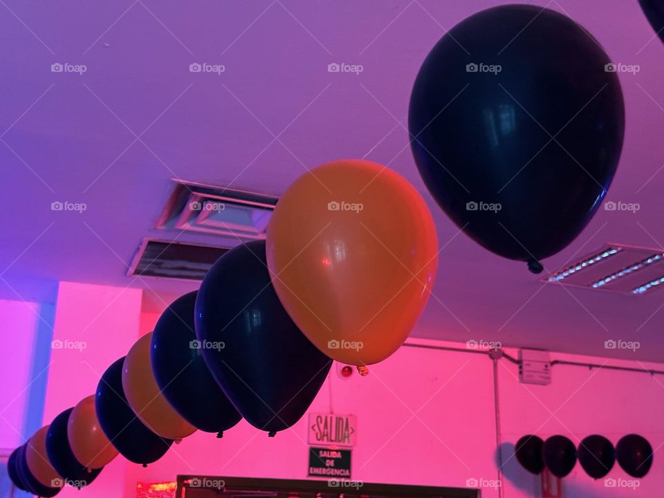 Orange and black balloons floating in a line, forming a pattern from corner to corner.