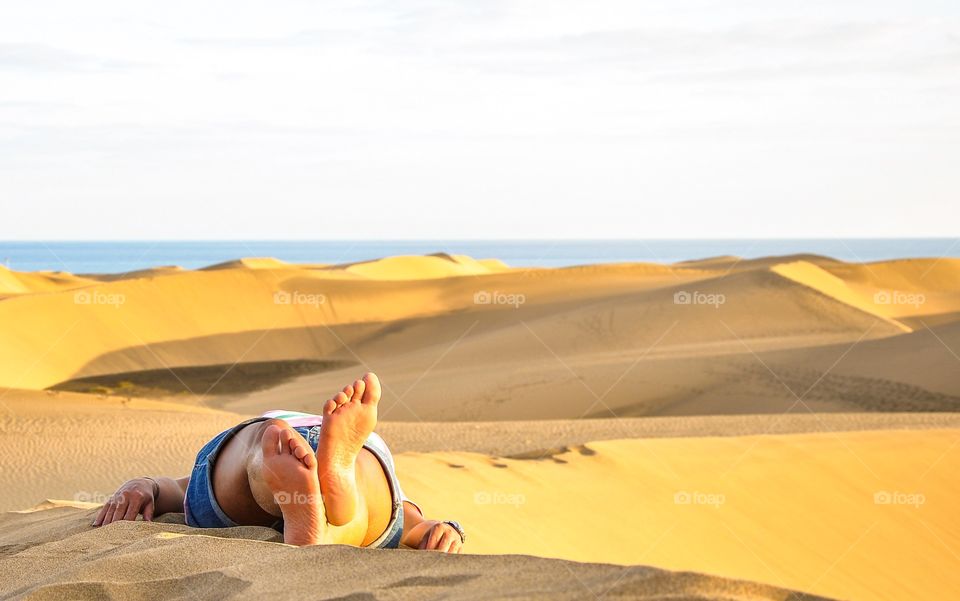 Person resting on sand dune