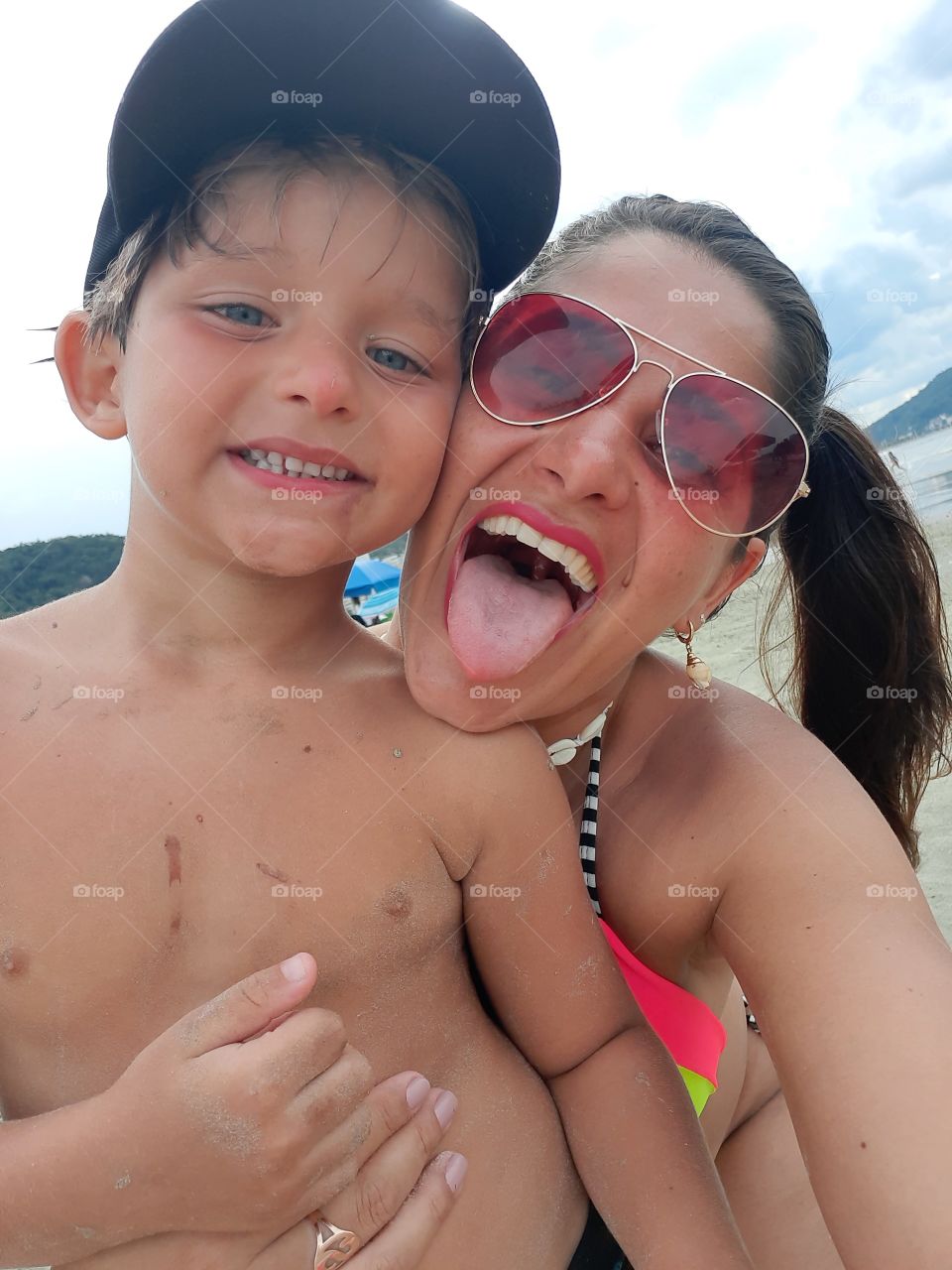 smiling child with mother sticking tongue on the beach