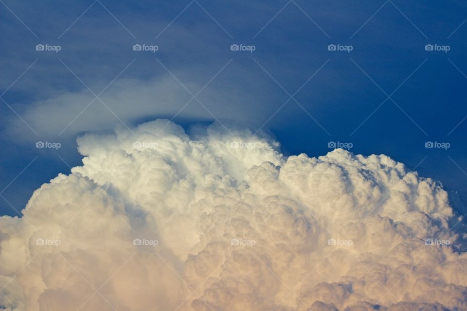 A giant cumulonimbus cloud illuminated by low-angled sunlight against blue sky  