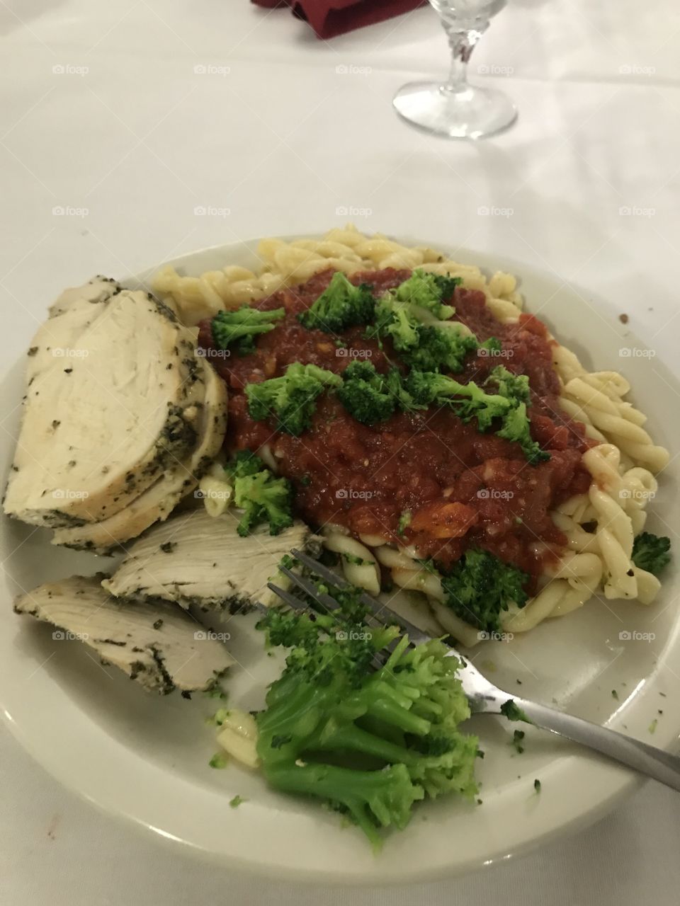 Delicious looking meal of pesto chicken over marinara pasta with broccoli florets, bright and colorful 