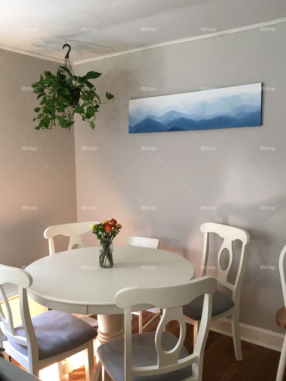 White dining table with hanging plant in a home.