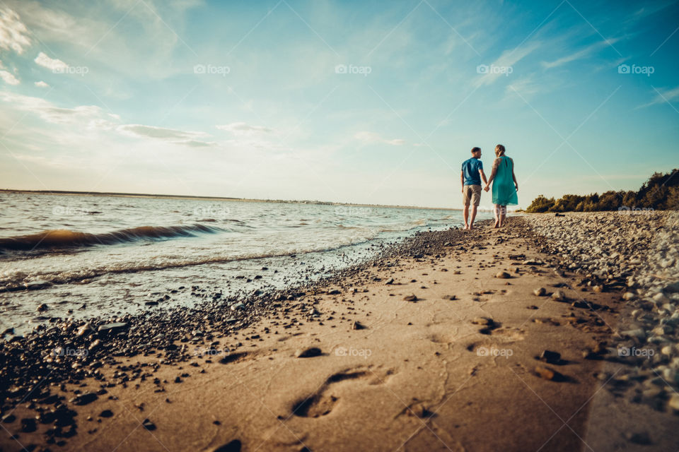 парень и девушка уходят вдоль берега оставляя следы на песке