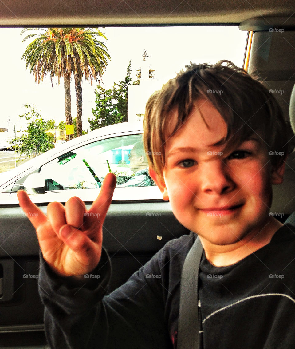 Young handsome boy rocking out and showing devil horns heavy metal