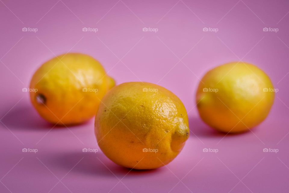 Three lemons on a pink background