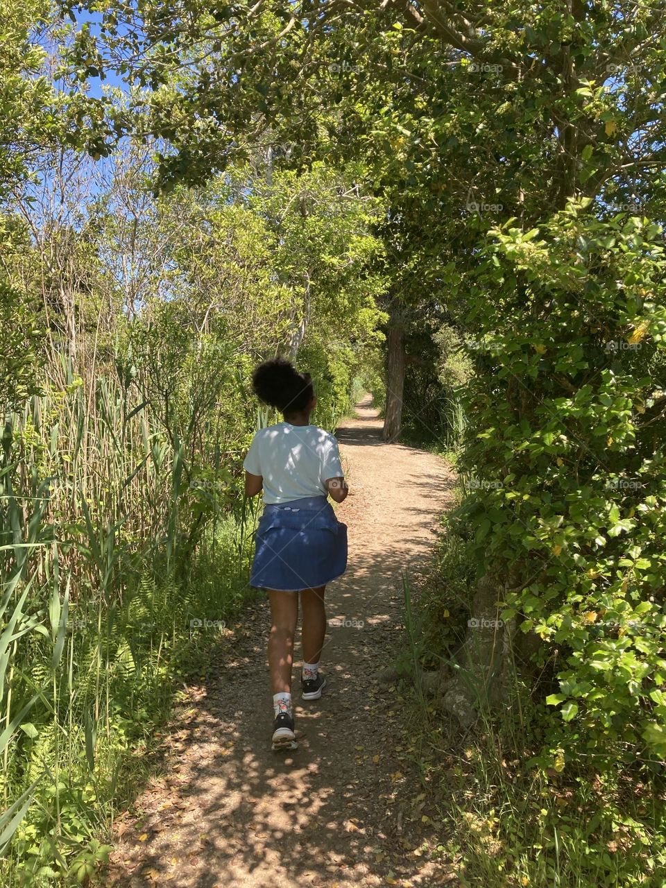 Girl walking through path in a park