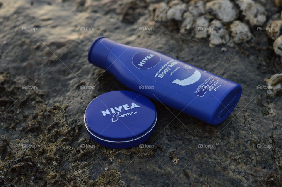 Nivea creme and Nivea body lotion are flaunted on the sea rock covered by beautiful Leathesia or Marine algae.