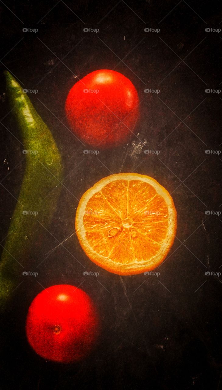 The tomatos, lemon and pepper are lying on the black Still life.