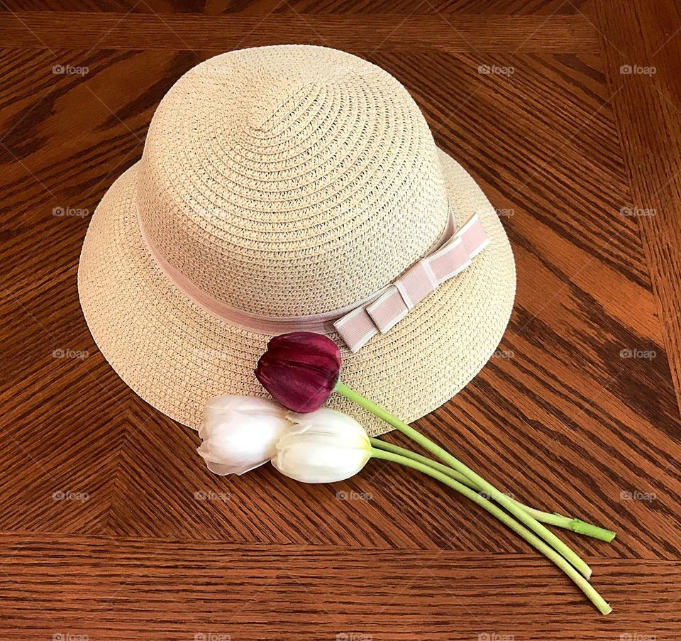 Sunhat and tulip flowers on table