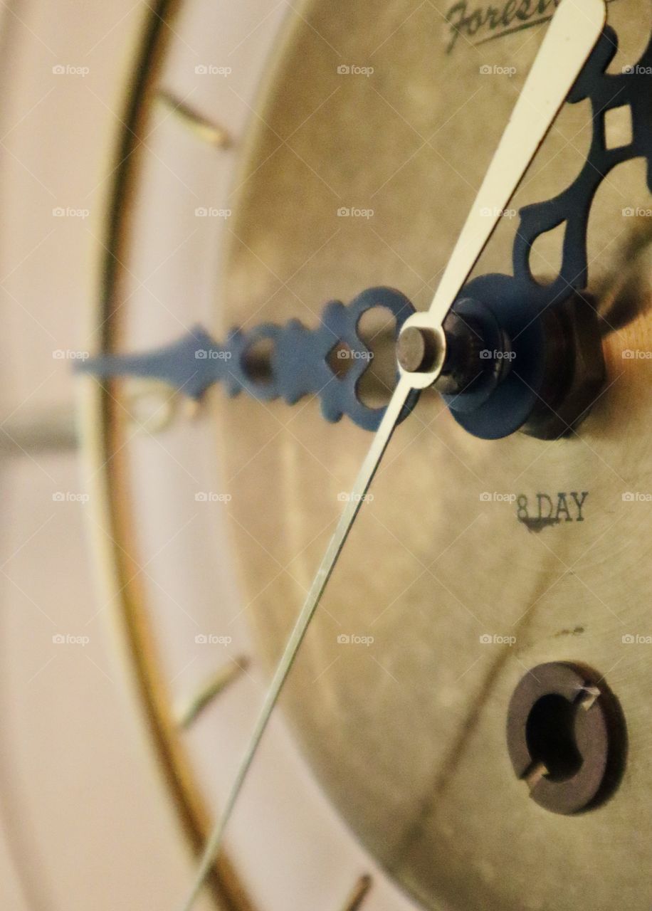 An antique gold and black clock hangs on a wall, illuminated by soft morning light