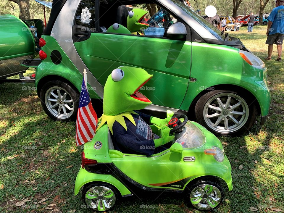 What makes you smile - so funny - Kermit the frog in a toy green Smart car along the side of a real green Smart car. The race is on.