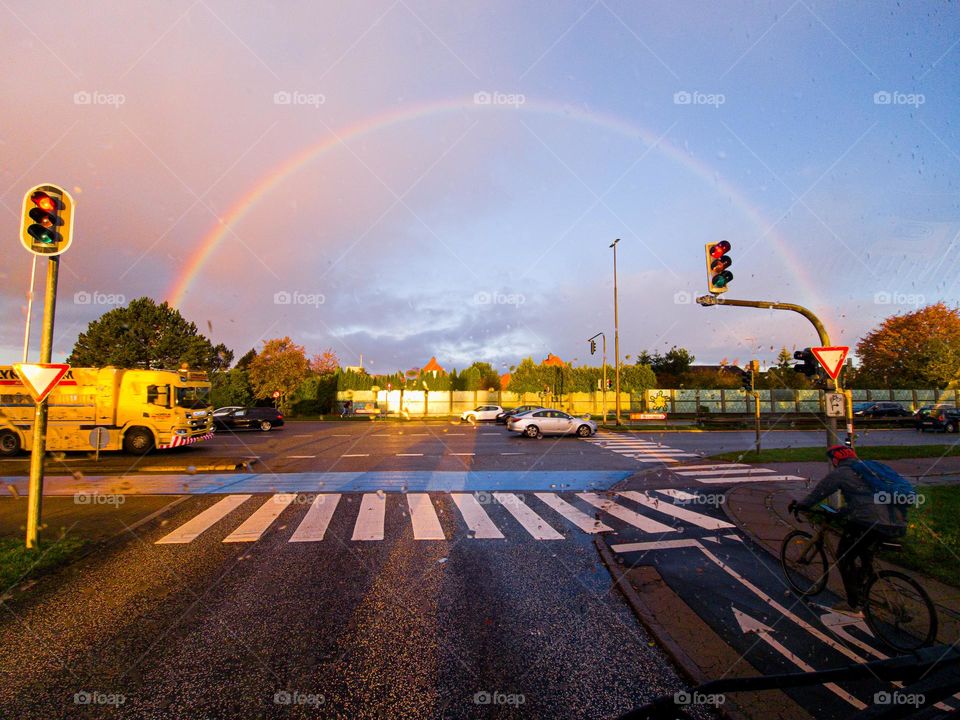 sunny autumn morning in the city at the crossroads with rainbow on the sky.