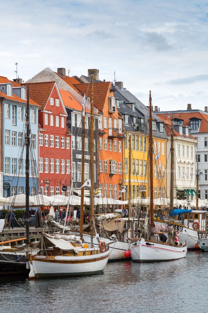 Nyhavn area in Copenhagen, Denmark. Colorful houses and sailboats. Nordic design. Touristic and famous spot. Water and cloudy sky. Restaurants next to the water