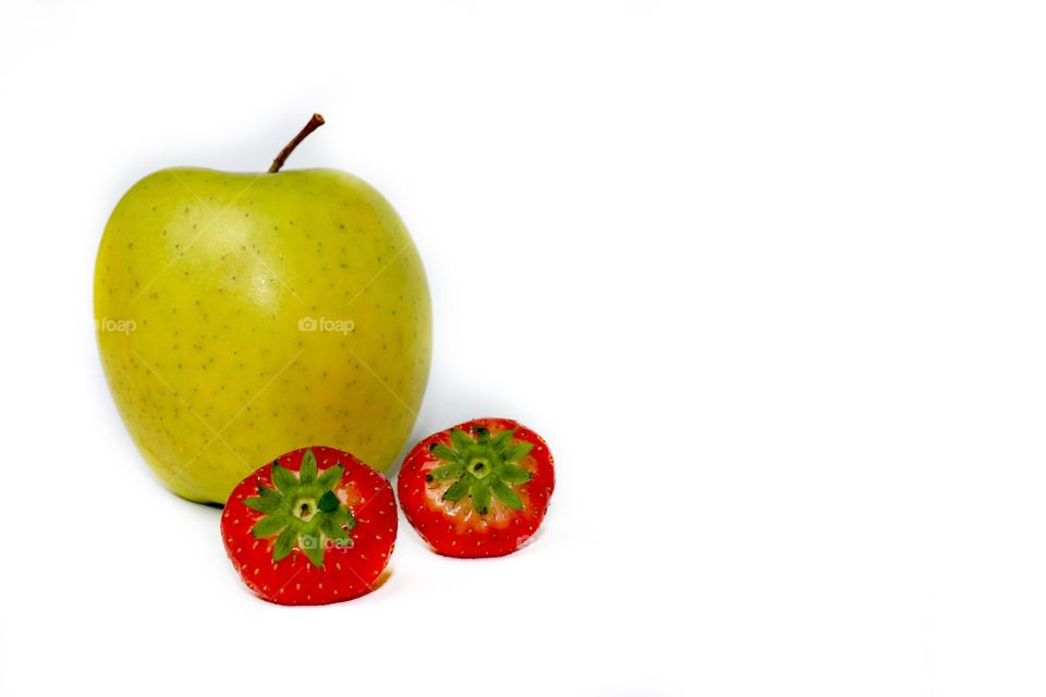 A green apple and two strawberries, isolated, white background 