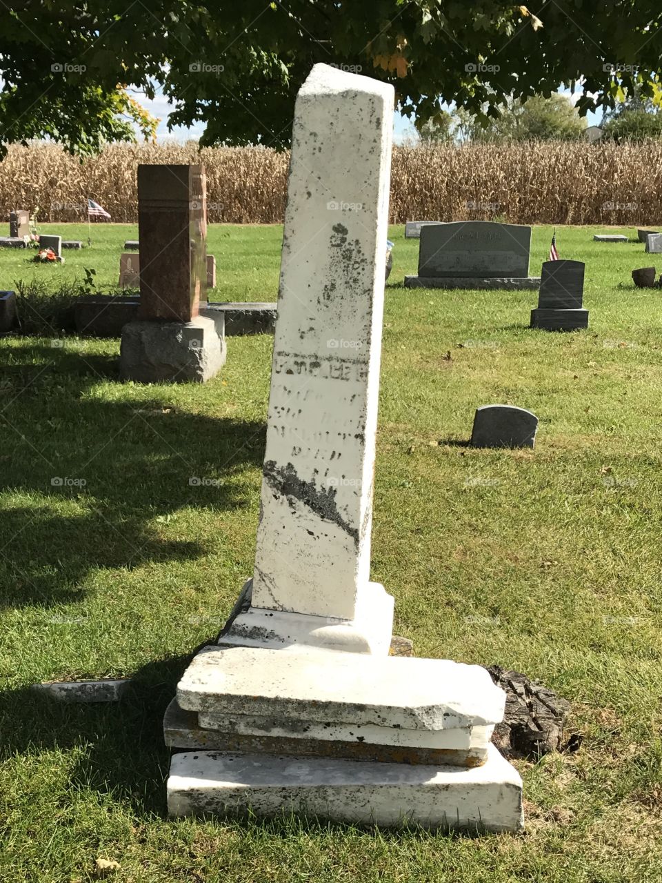 Very old monument with a stack of headstones in front.