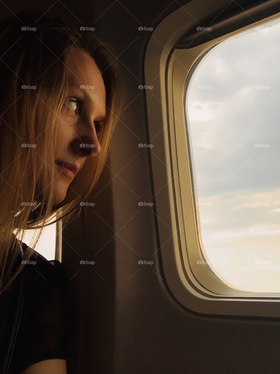 Woman look at sunset in plane window illuminator 