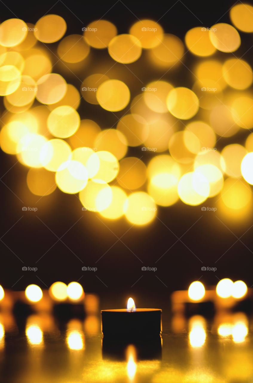 Burning candles with festive holiday bokeh background close up. Top view, flat lay. Christmas and holiday celebration concept. Hope and pray.