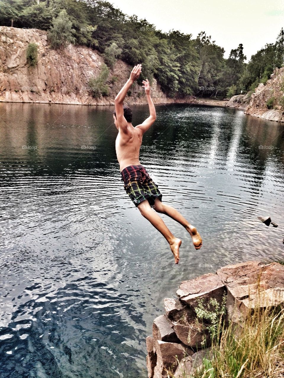 Boy from behind jumping into quarry