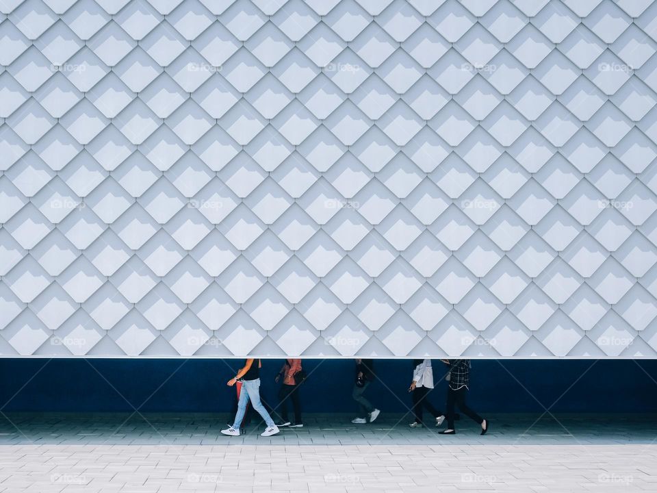 A family walking under cover behind a white shingles facade