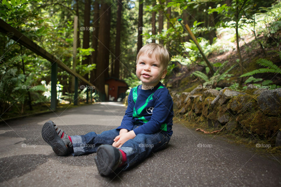 Young Boy sitting on pavement in national park 