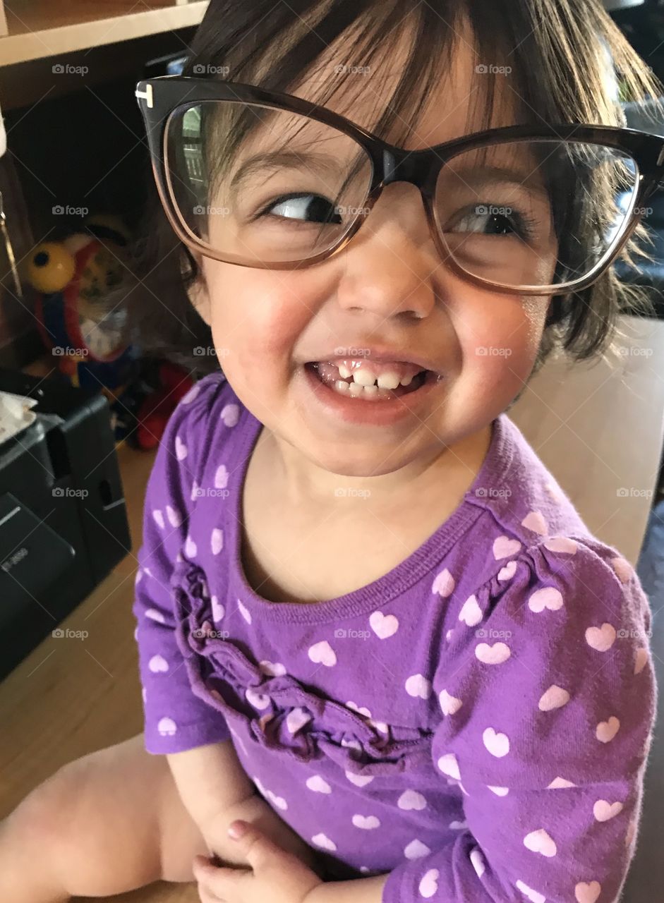 Baby girl laughing while trying on big glasses