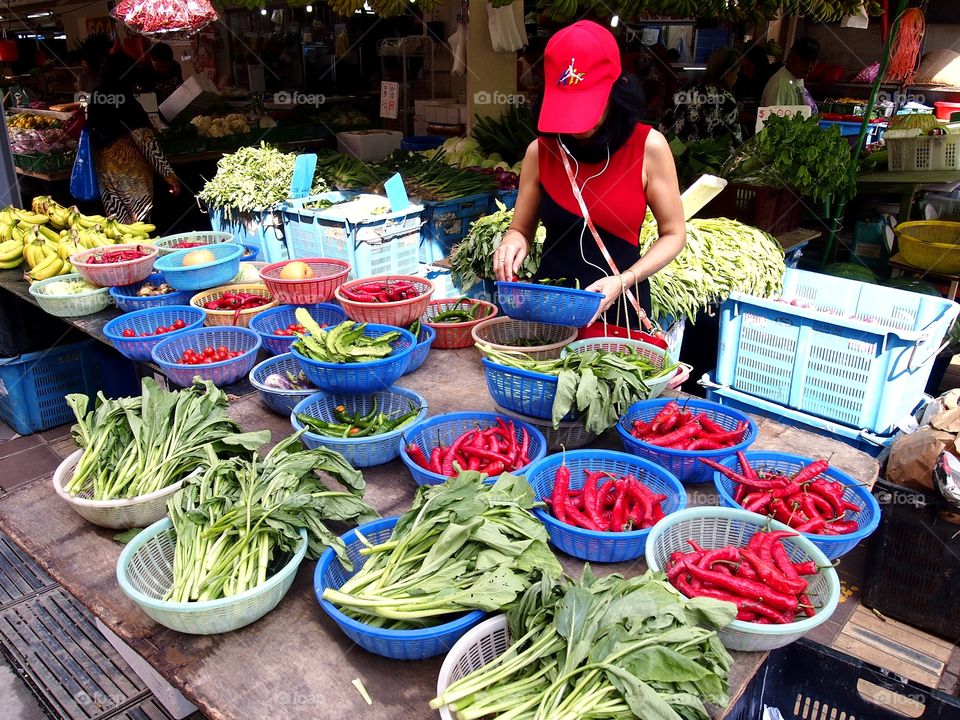 a lady buying fruits and vegetables at a market