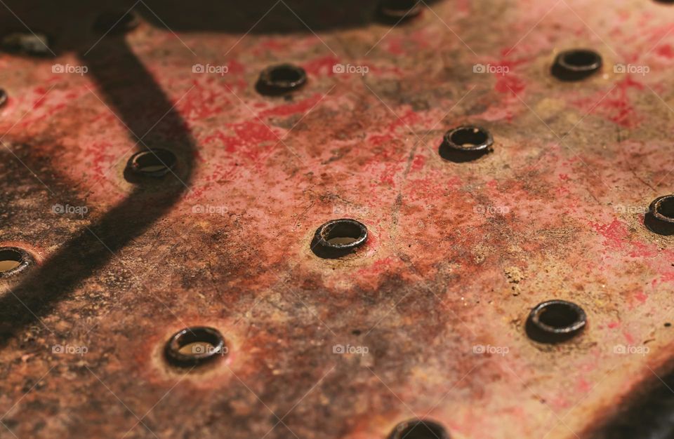 Circles in rust metal plate with dramatic sunlight