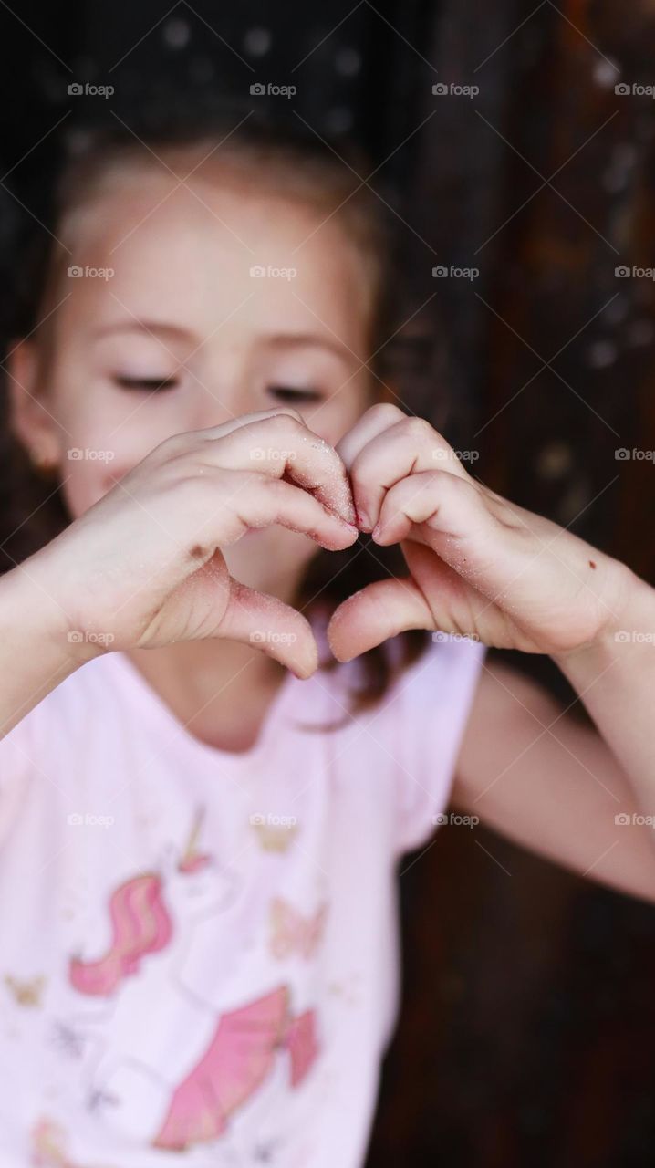 Little girl making heart with her hands