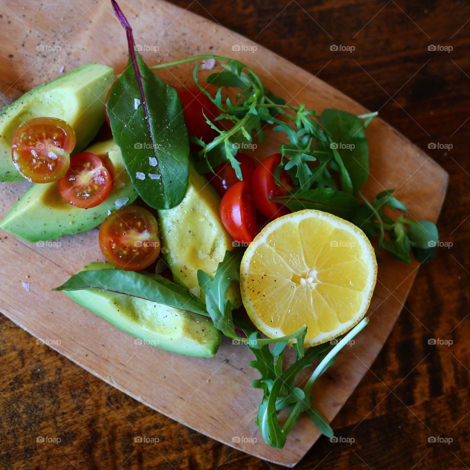 Wooden plate with avocado salad 