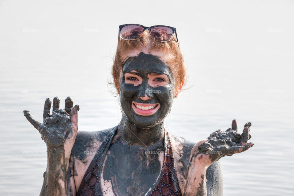 Young woman applying face mask on face