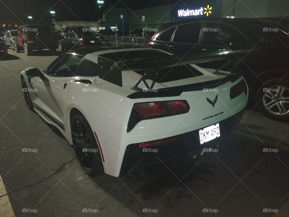 Corvette with a rear spoiler in Walmart parking lot.