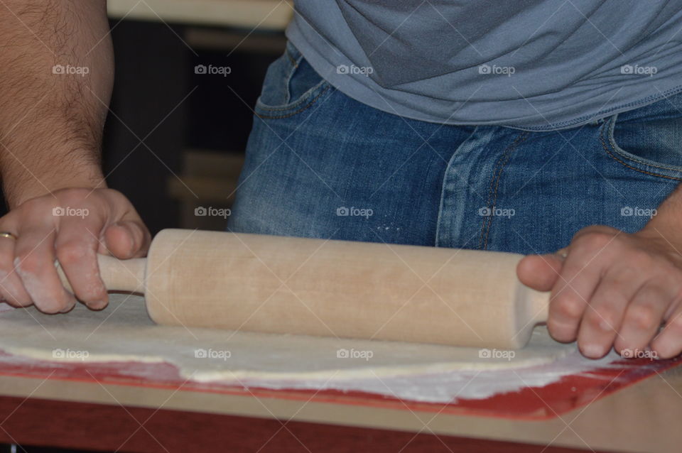 Cropped hands using rolling pin at table in kitchen