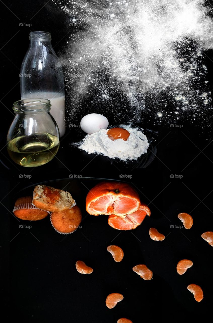 Photo flip. Cooking tangerine cupcakes. The black background is divided. At the top are the ingredients: milk in a bottle, butter in a jar, white flour and an egg. Bottom of cupcakes and tangerine slices