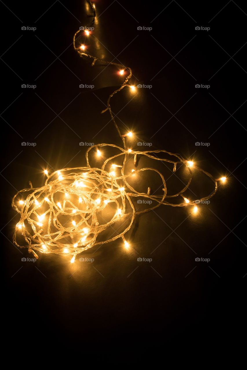Diwali chain light, spiral shape, design to decorate street or home fireworks, dark black background shot in festival time or new years eve carnival, copy space. Remove darkness, decoration concept