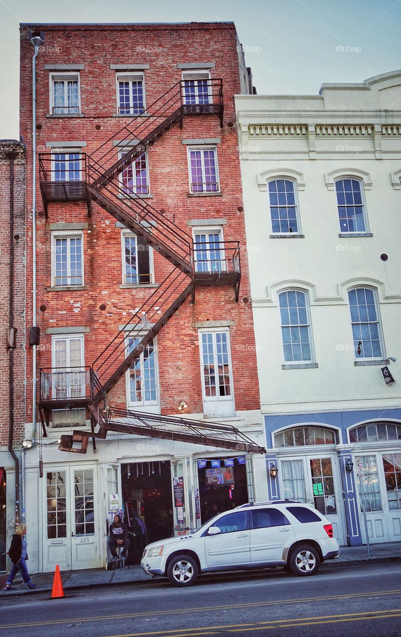 Old style apartments on an inclined road. Ground floor spaces are reserved for shops. French Quarter, New Orleans, Louisiana, USA.